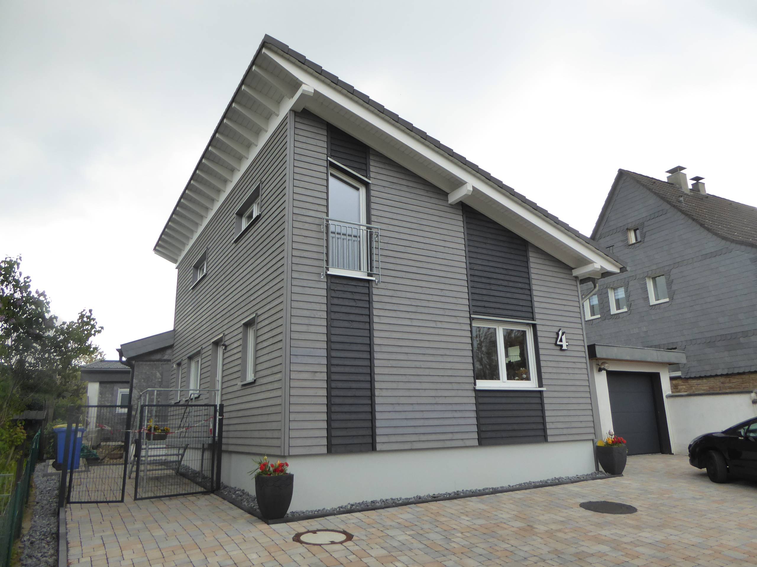 Zweigeschossiger Anbau aus Holz mit Pultdach im Garten eines Wohnhauses