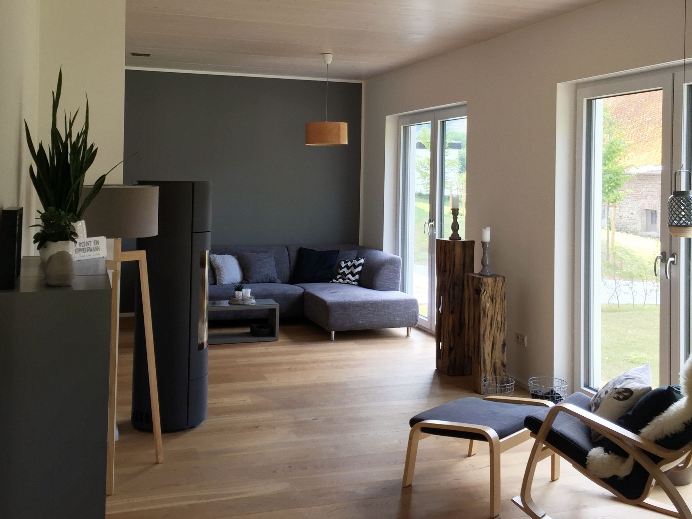 Wohnzimmer im Holzhaus mit Kamin, Holzfußboden und großer Fensterfläche