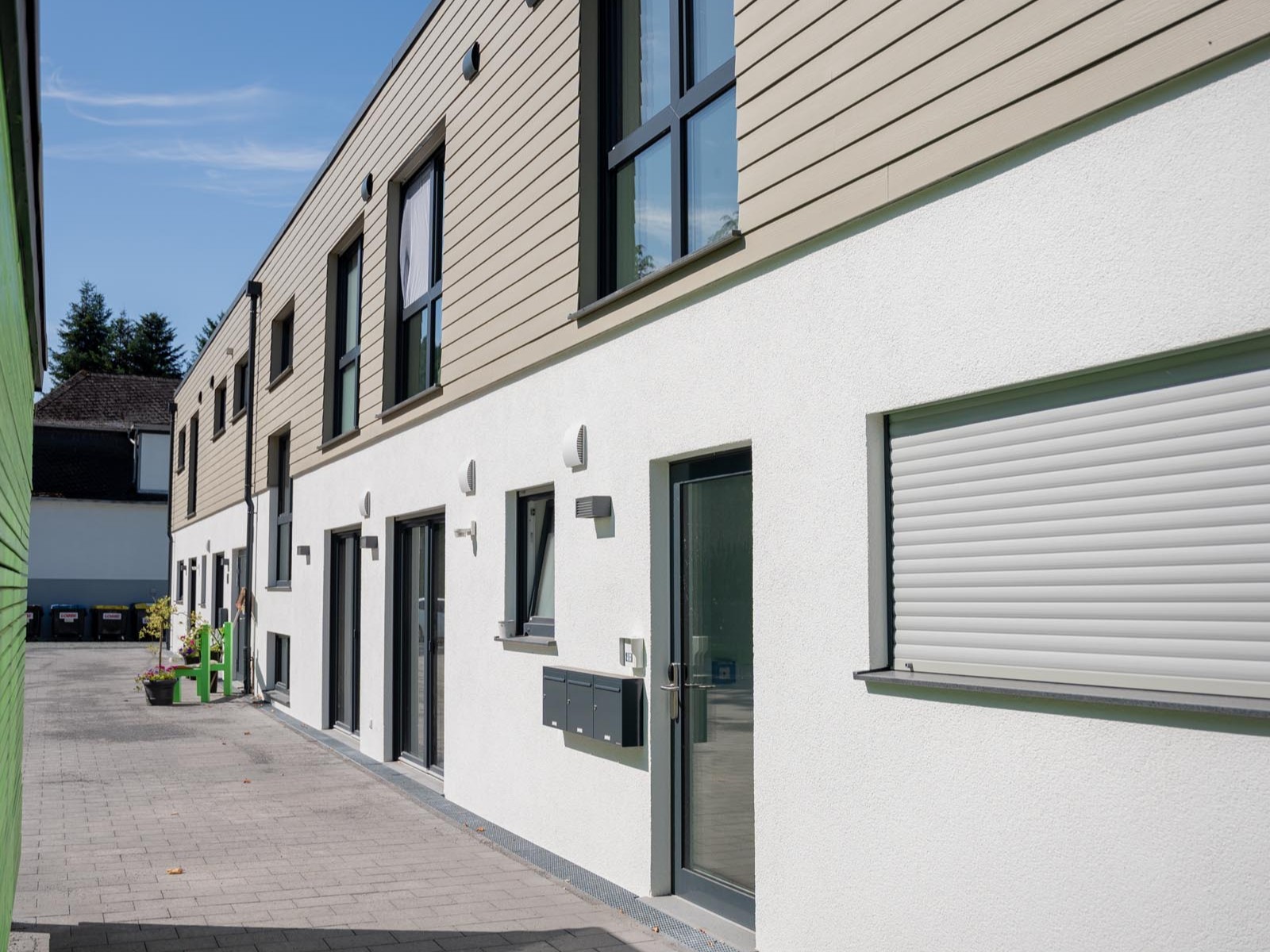 Erschließungsweg entlang der Außenwohngruppe mit Eingängen und Holzfassade.